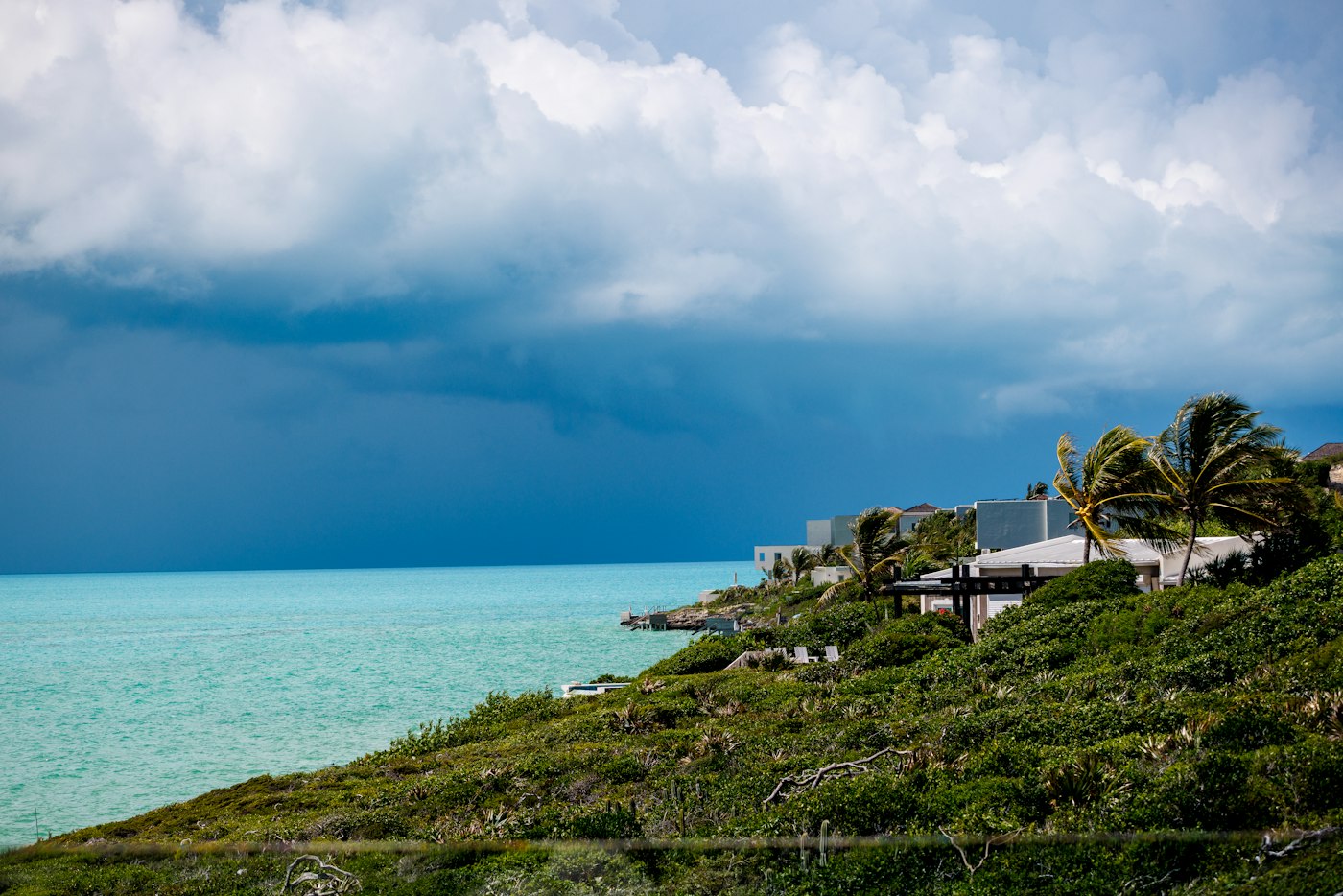 Storm clouds gathering over a tropical coastline with homes